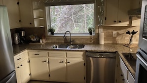 A kitchen with a window, sink, cabinets, and a dishwasher. - Suburb in the City (Atlanta)