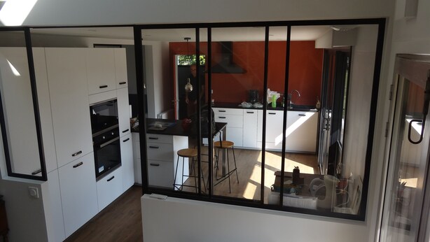 Una cocina moderna con armarios blancos, encimera negra y una pared de acento roja.