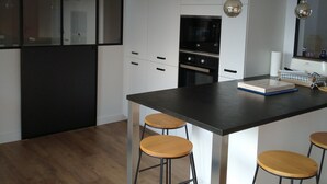 Una cocina moderna con armarios blancos, una encimera negra y tres taburetes de madera.