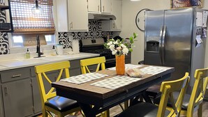 Une cuisine moderne avec une table à manger, des chaises jaunes et un réfrigérateur en acier inoxydable.