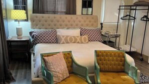 Une chambre à coucher avec un grand lit, deux chaises, une table de chevet, une lampe, un lampadaire et une armoire.