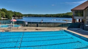 Piscina com vista para um lago e um edifício ao fundo.