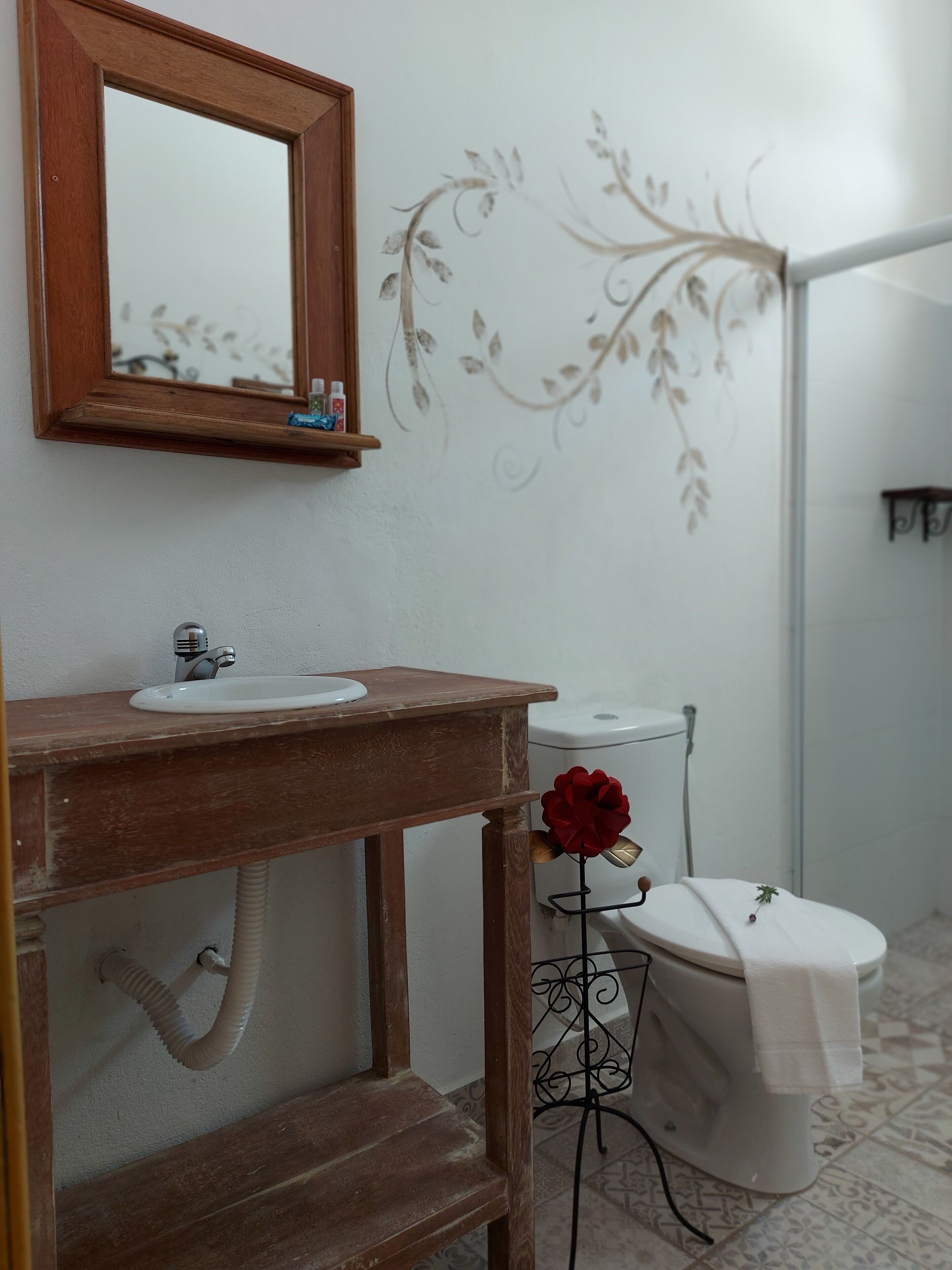 Ein Badezimmer mit einem Holzkonsolenunterschrank, einem weißen Waschbecken, einem Spiegel und einer Toilette.