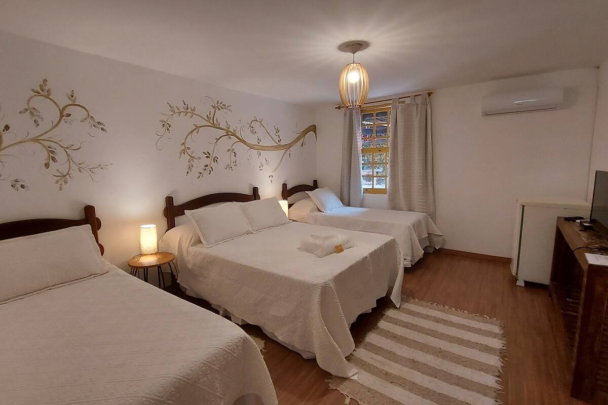 Habitación de hotel con dos camas, un escritorio, un televisor y una ventana con cortinas.