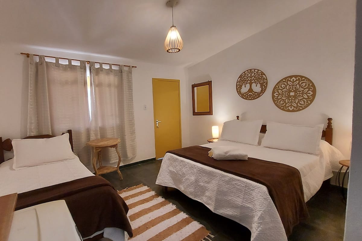 Habitación de hotel con dos camas, una mesita, una silla, televisor y decoración en la pared.