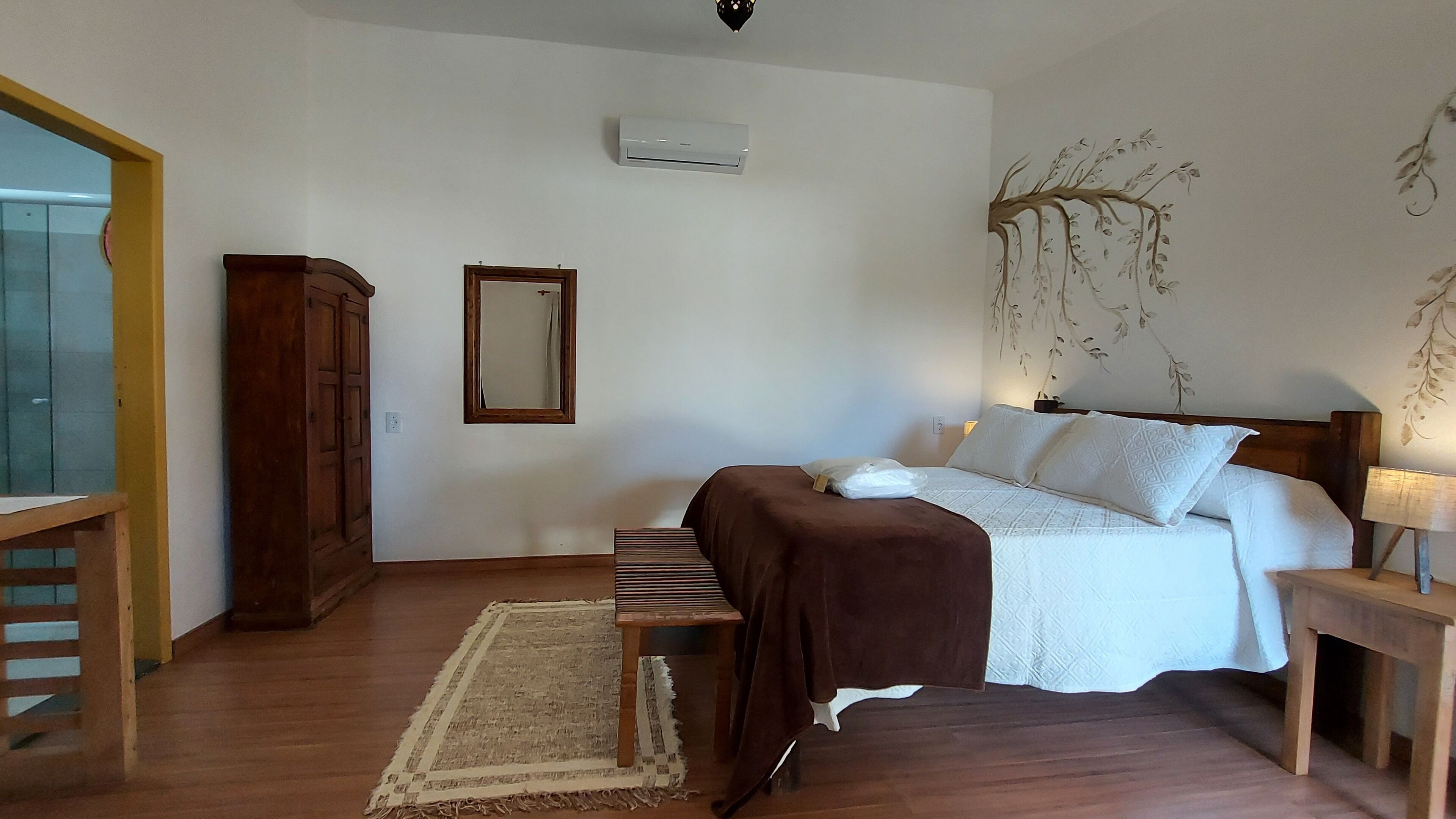 A bedroom with a bed, bedside table, lamp, and a mirror on the wall.