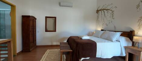 Un dormitorio con cama, mesita de noche, lámpara y un espejo en la pared.
