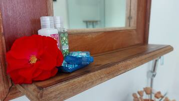 A wooden shelf with toiletries and a red flower.