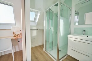 A modern bathroom with a glass shower enclosure, a white vanity, and a skylight above the shower. - Entire House in Lorient, Near the Beaches and City Center   (Lorient)