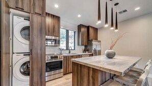 A modern kitchen with built-in appliances, a marble countertop, and wooden cabinetry.