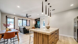 A modern kitchen with a central island, wooden cabinetry, and a dining area with a table and chairs.