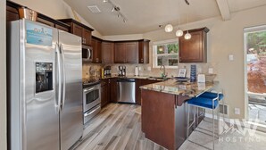 A modern kitchen with stainless steel appliances, wooden cabinets, and a large island. - Luxurious Echo Bay Retreat—Hot Tub, Fire Pit, Ping Pong, Chess, Bikes & Stunning Views Await! (Harrison)
