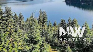 A serene lake surrounded by dense forests. - Luxurious Echo Bay Retreat—Hot Tub, Fire Pit, Ping Pong, Chess, Bikes & Stunning Views Await! (Harrison)