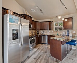 Une cuisine moderne dotée d’appareils électroménagers en acier inoxydable, de meubles en bois et d’un grand îlot central.