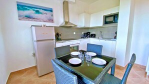 Une cuisine compacte équipée d’un réfrigérateur, d’un four à micro-ondes et d’une table à manger avec des chaises.