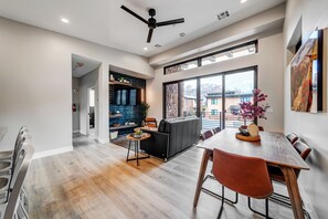 A modern kitchen with a dark backsplash, a dining area with a wooden table and chairs, and a large window offering a view of the outside. - LaFave-Luxury Villa at Zion: Orderville Canyon (Springdale)