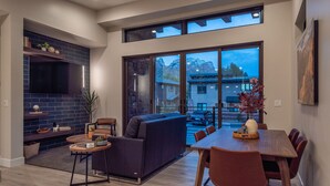 A modern dining area with a large window, a sofa, and a dining table with chairs. - LaFave-Luxury Villa at Zion: Orderville Canyon (Springdale)