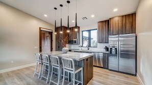 A modern kitchen with a central island, stainless steel appliances, and a wooden finish. - LaFave-Luxury Villa at Zion: Orderville Canyon (Springdale)