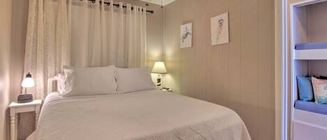 A bedroom with a bed, a nightstand, a lamp, a ceiling fan, and a door leading to a balcony.