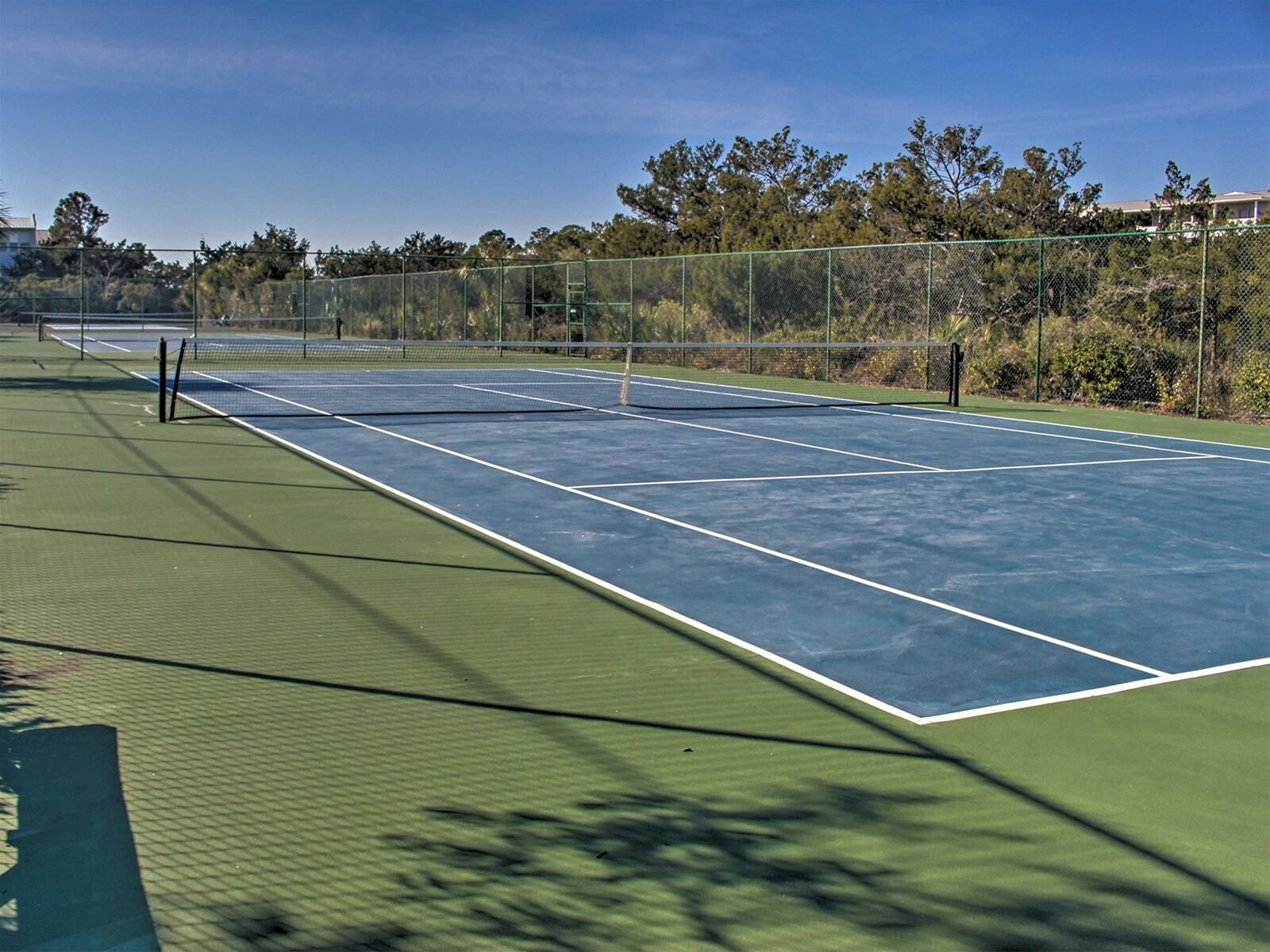 Un court de tennis avec une surface verte et des lignes de démarcation bleues.