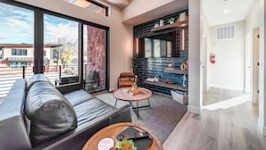 Een moderne woonkamer met een leren bank, een ronde salontafel en een open haard.