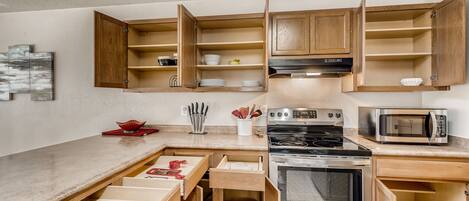 A modern kitchen with wooden cabinetry, built-in appliances, and a countertop with a microwave and stove.