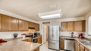 Una cocina con gabinetes de madera, electrodomésticos de acero inoxidable y encimera de granito.
