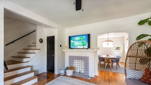 Een moderne woonkamer met een open haard, een eethoek en een trap.