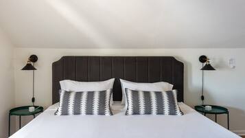 A neatly made bed with a dark headboard, two bedside tables with lamps, and patterned pillows.