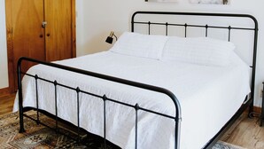A bedroom with a bed, wooden wardrobe, and a patterned rug.