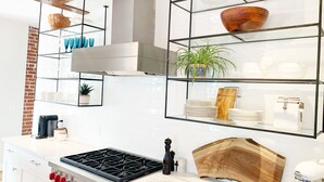 Une cuisine moderne avec une cuisinière à gaz, des armoires blanches et un mur en briques.