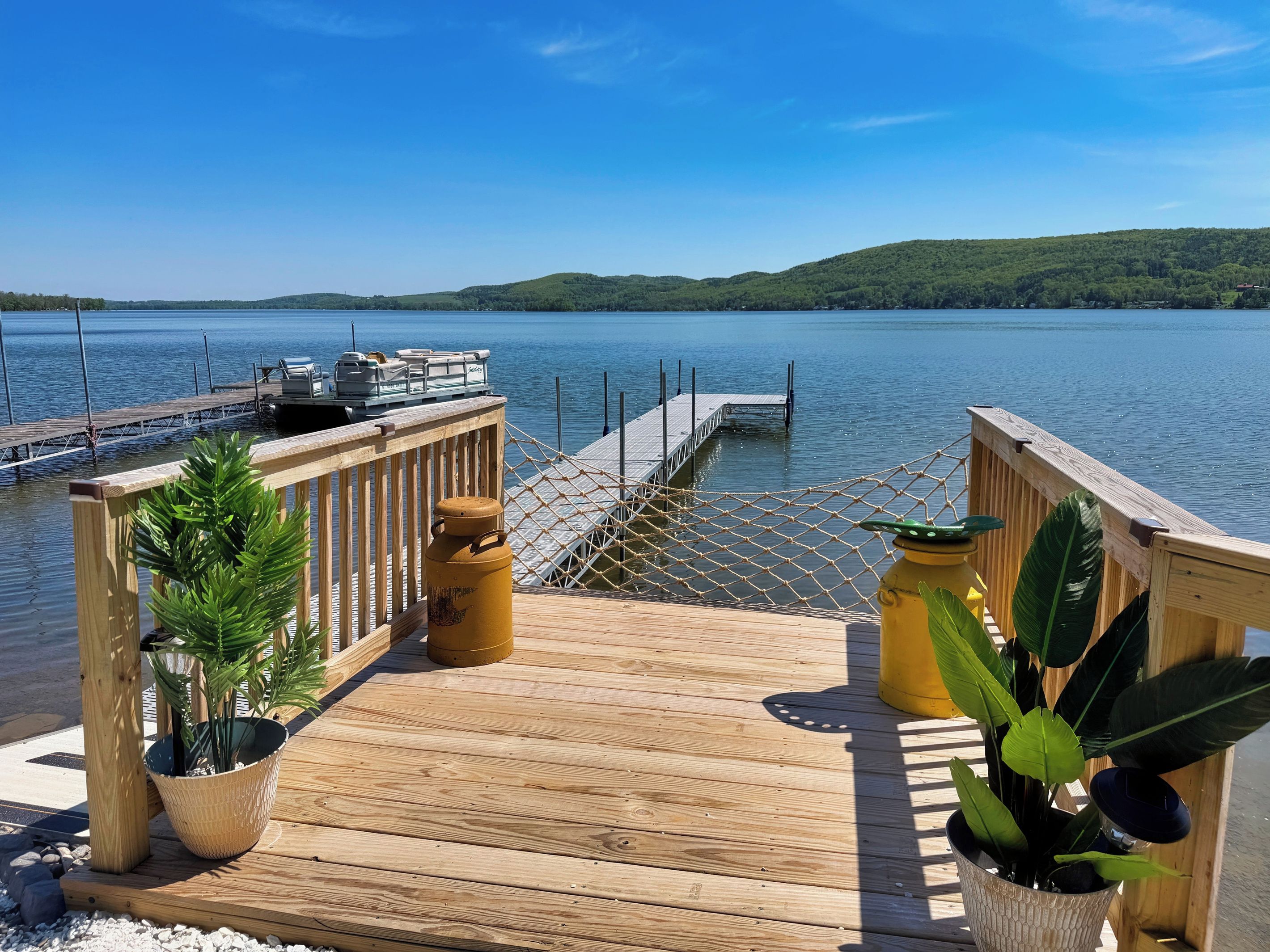 Une terrasse en bois offrant une vue sur un lac et un quai.