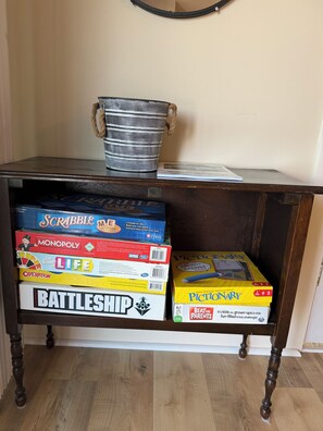 A wooden shelf with various board games and a metal bucket.
