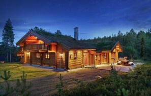 A log cabin with a porch, a chimney, and a small deck.