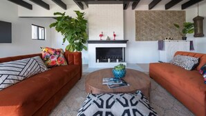 Una sala moderna con dos sofás naranjas, una chimenea y una planta grande.