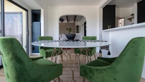 Un comedor con una mesa redonda, sillas tapizadas en verde y un diseño moderno.