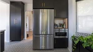 Una cocina moderna con refrigerador de acero inoxidable, muebles oscuros y piso de baldosas.