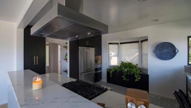 Una cocina moderna con una isla grande, electrodomésticos de acero inoxidable y un salpicadero negro.