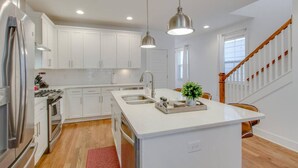 A modern kitchen with white cabinetry, stainless steel appliances, and pendant lighting.