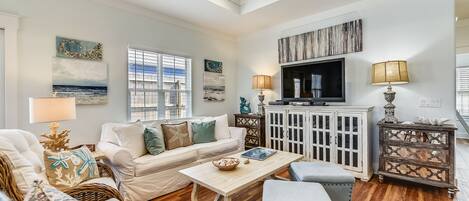 A spacious living room with a white sofa, a coffee table, and a television.