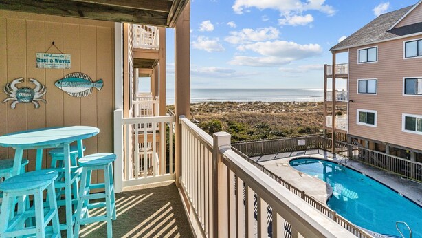 Un balcon avec une piscine, une vue sur la plage et une enseigne indiquant « Cast-a-Waves ».
