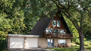 A two-story house with a large garage, a balcony, and a view of the ocean. -  Riverview Cabin home! (Stoddard)