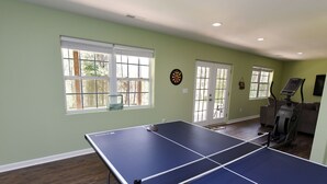 A room with a ping pong table, exercise equipment, and large windows with blinds. - Spacious Family Mountain Gem Nestled in Nature-5 min to Historic Murphy!  (Murphy)