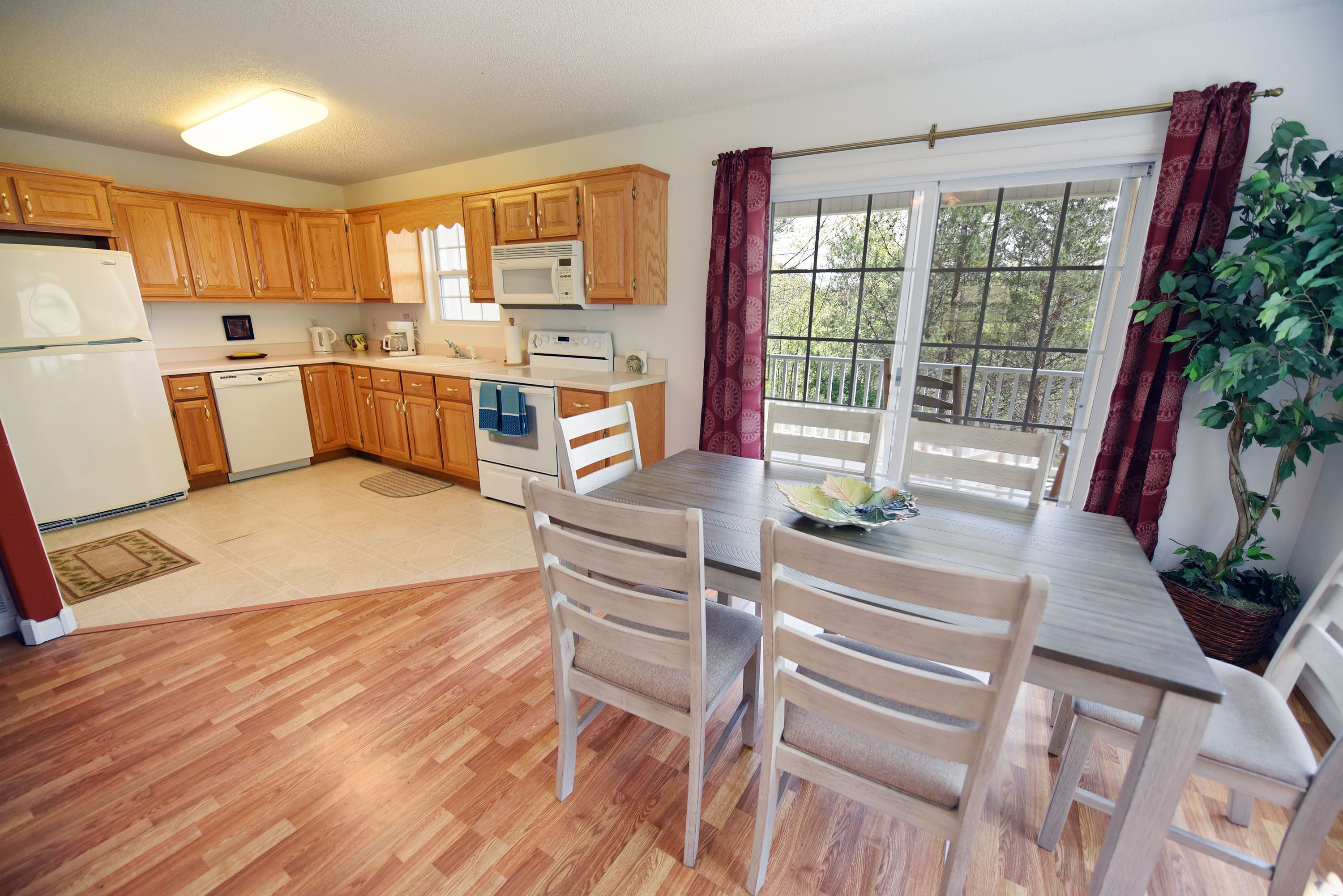 Une cuisine avec des meubles de rangement en bois, un réfrigérateur, un four à micro-ondes et une table à manger avec des chaises.