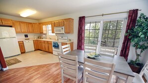 A kitchen with wooden cabinets, a refrigerator, a microwave, and a dining table with chairs. - Spacious Family Mountain Gem Nestled in Nature-5 min to Historic Murphy!  (Murphy)