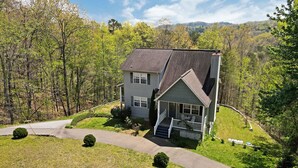 A two-story house with a front porch, surrounded by a well-maintained lawn and trees. - Spacious Family Mountain Gem Nestled in Nature-5 min to Historic Murphy!  (Murphy)