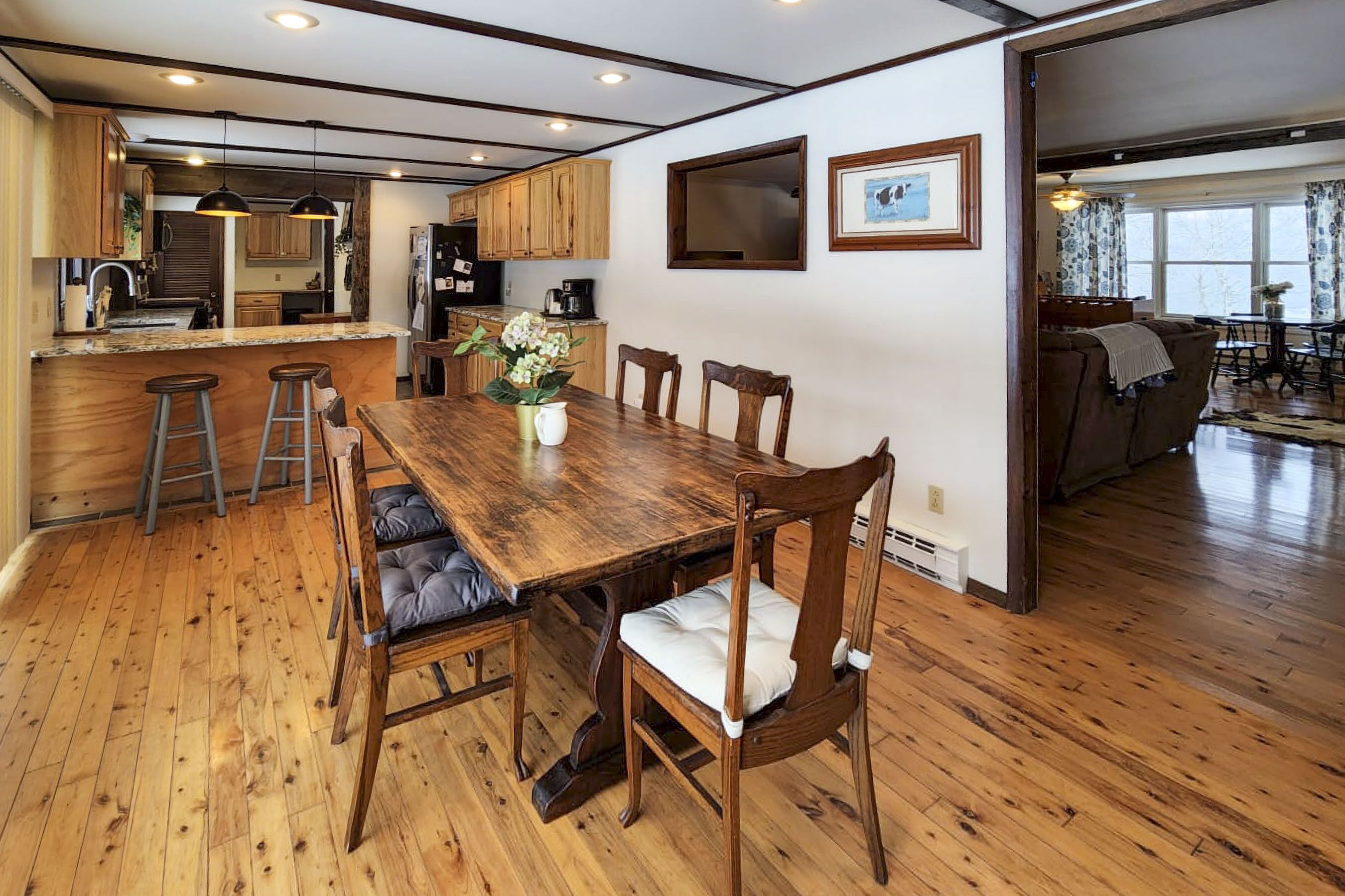 A spacious kitchen with wooden cabinets, a central island with stools, and a dining area with a wooden table and chairs.