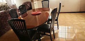 A dining area with a round table, six chairs, and a patterned sofa.