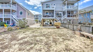 Una zona residencial frente a la playa con varias casas de dos pisos, balcones, patio de arena y cerca de madera.