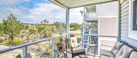 A covered outdoor deck with a sofa, a chair, and a hanging planter.